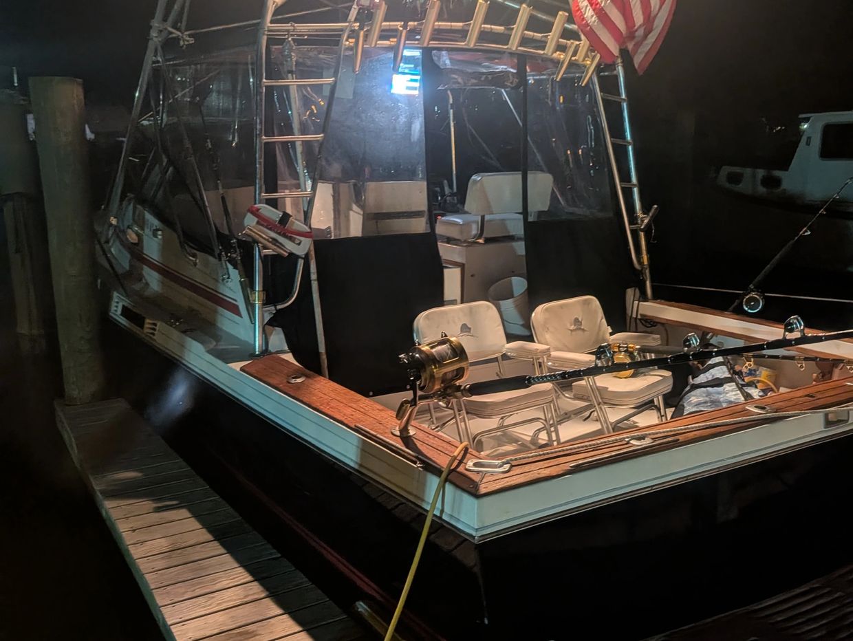 Fishing boat docked at night with chairs and fishing rods.