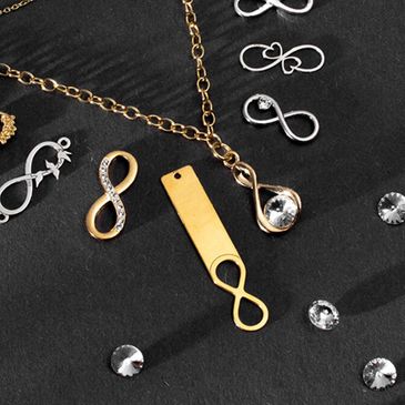 Various infinity symbol pendants and charms on a black surface.