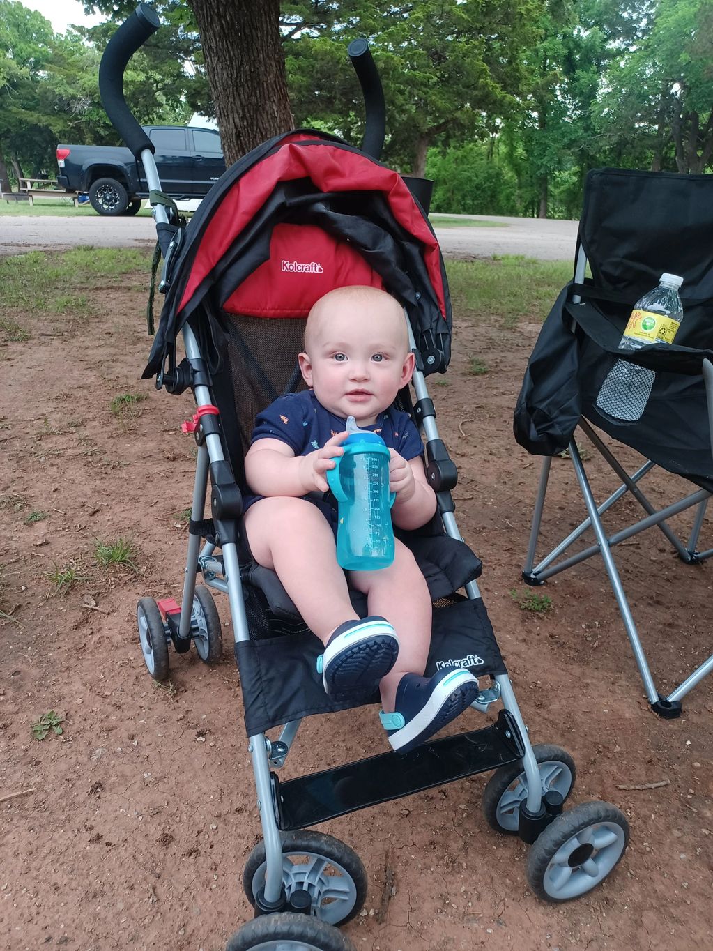toddler in stroller holding bottle at campgrounds