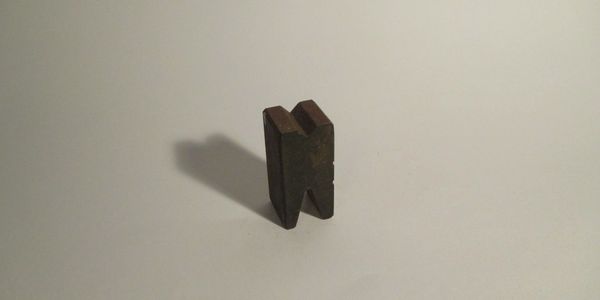 Old rusty metal tool with a V-shaped groove on a plain background.