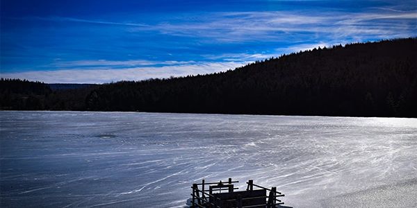Frozen lake under a clear blue sky with silhouetted hills.