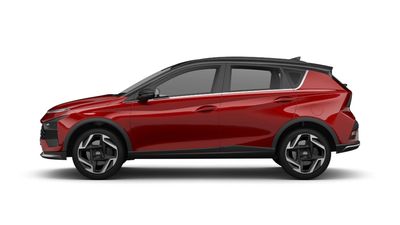 Side view of a sleek red modern SUV with black roof and stylish rims.