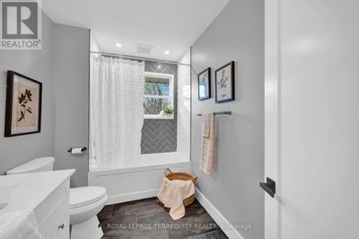 Modern bathroom with white tub, gray walls, and framed art.