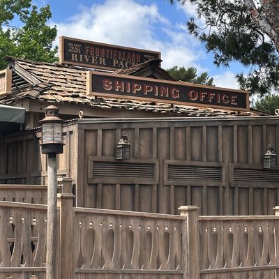 Rustic wooden building labeled Shipping Office at Frontierland River Pack.