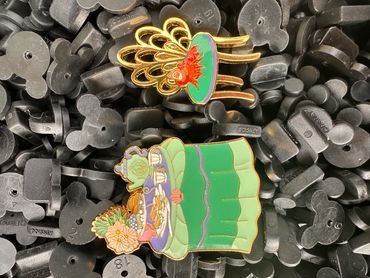 Two colorful decorative pins with floral and teapot designs.
