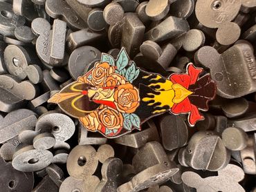 Colorful floral dagger pin on gray letter blocks.