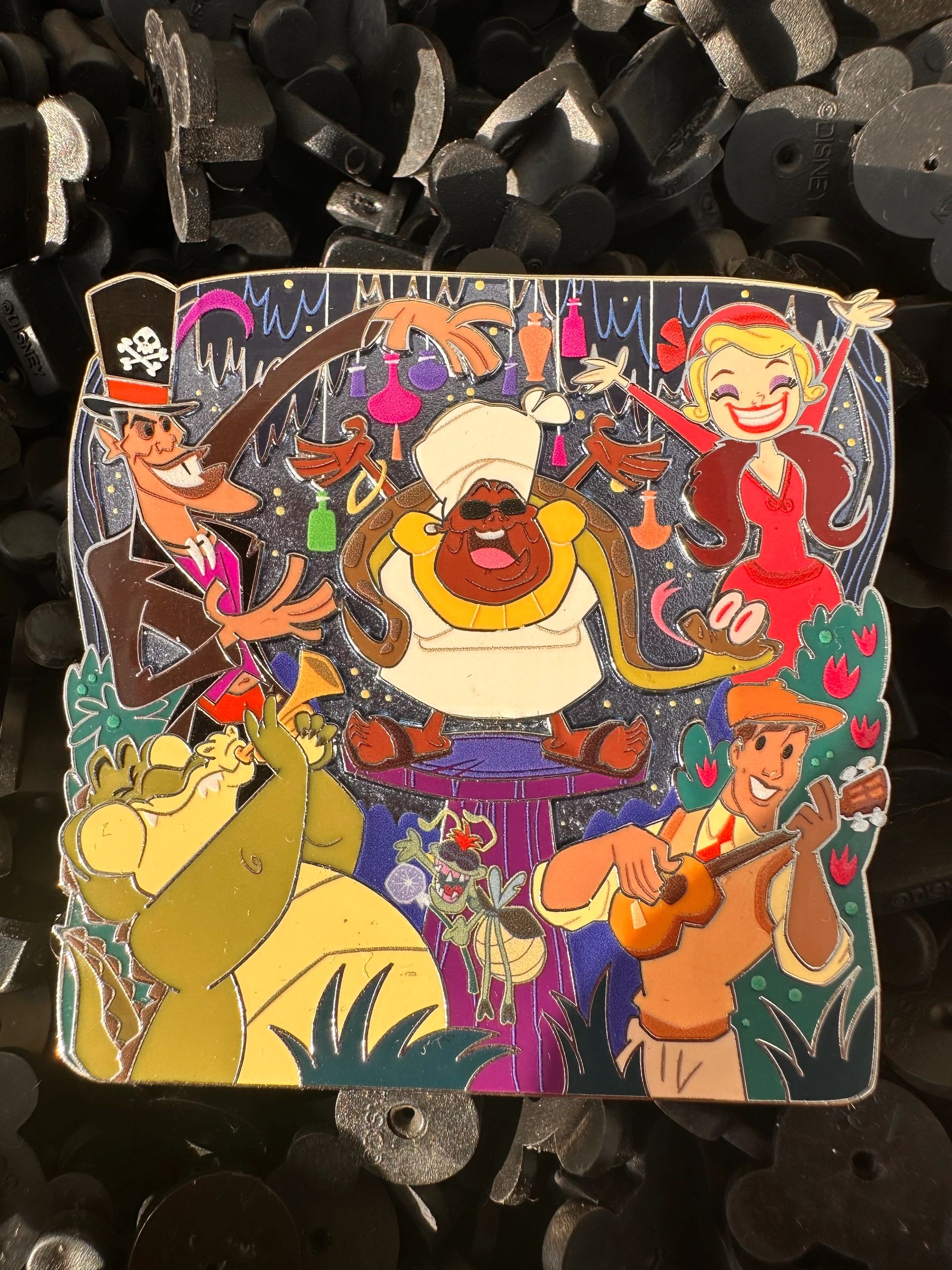 A colorful enamel pin featuring cartoon characters from The Princess and the Frog.