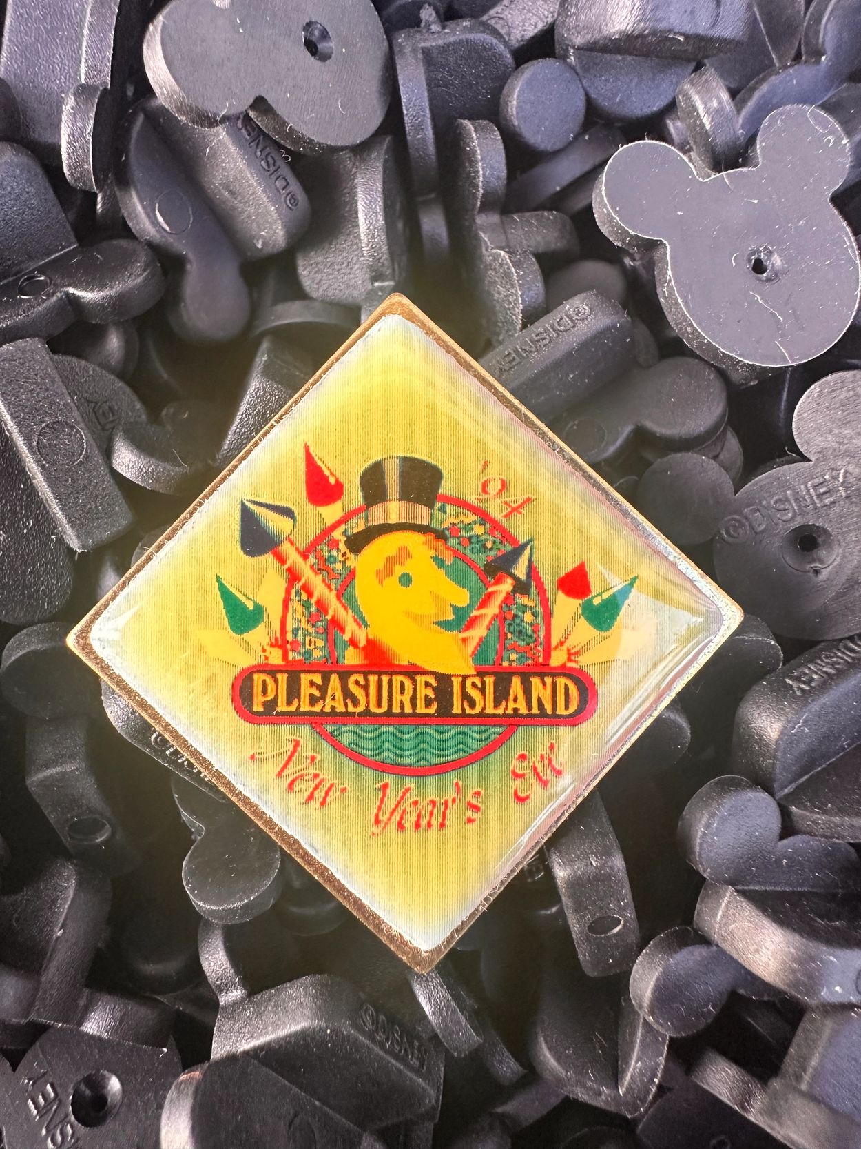 Pleasure Island souvenir pin from 1994 surrounded by black Mickey-shaped pieces.