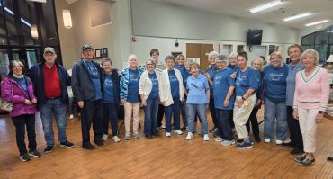 A group of people posing indoors, some wearing matching blue shirts.