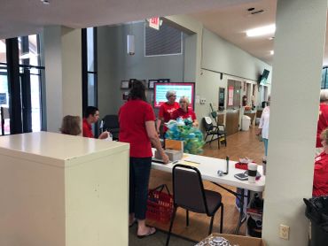 Volunteers in red shirts organizing items at a community center table.