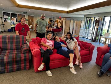 Group of five people relaxing on sofas in a cozy indoor setting.
