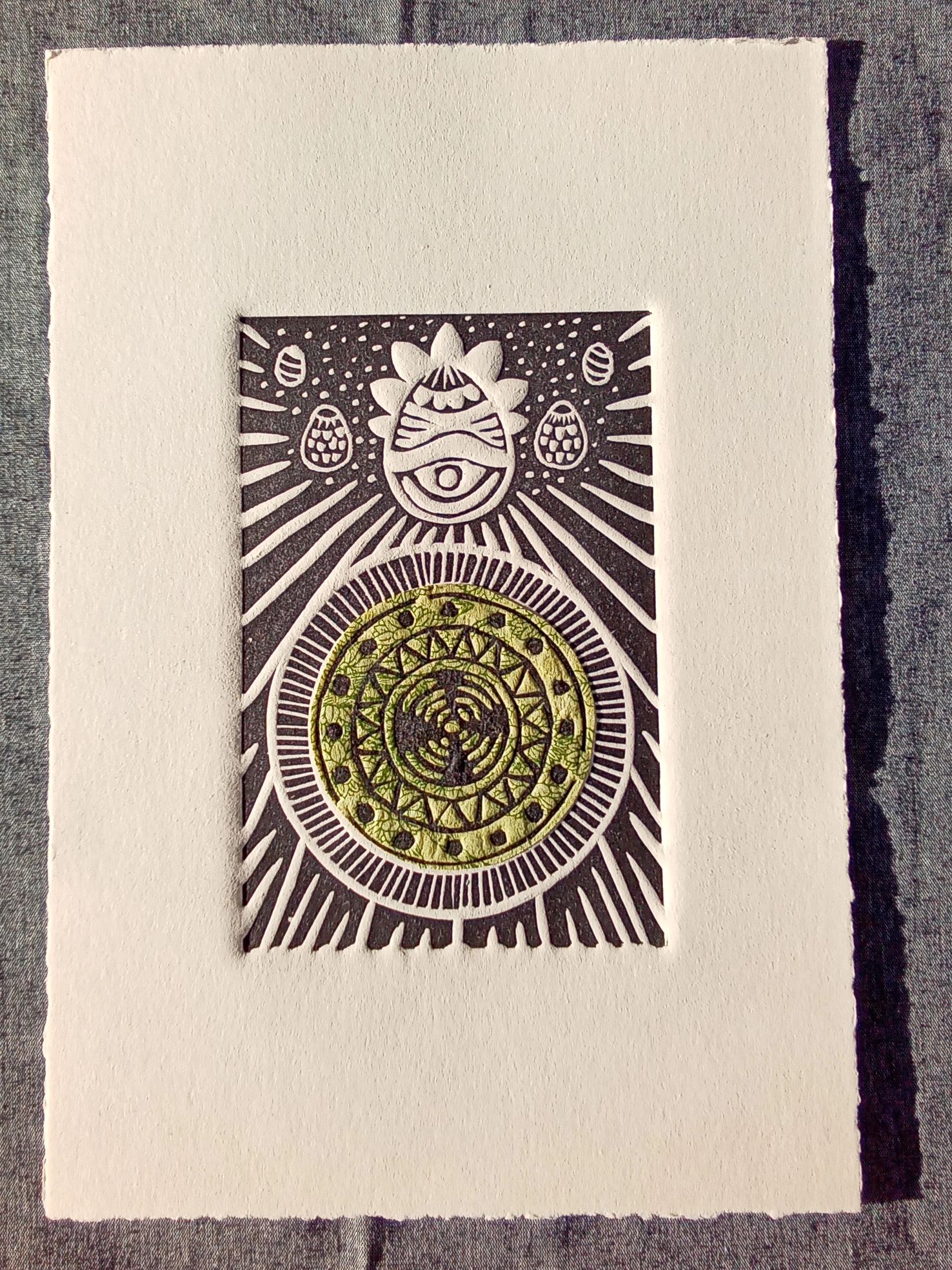 Intricate linocut print with circular and eye motifs in black and green.