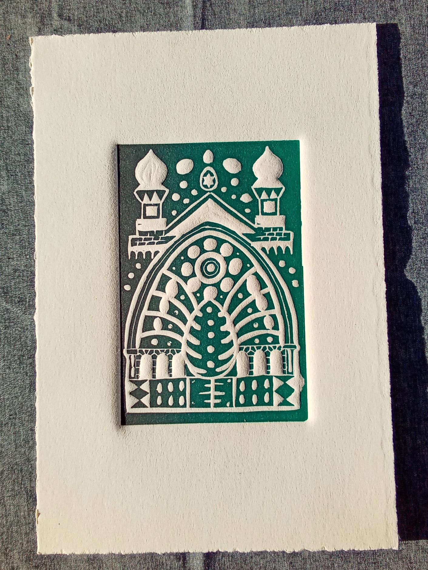 Intricate green and white relief artwork on textured paper.