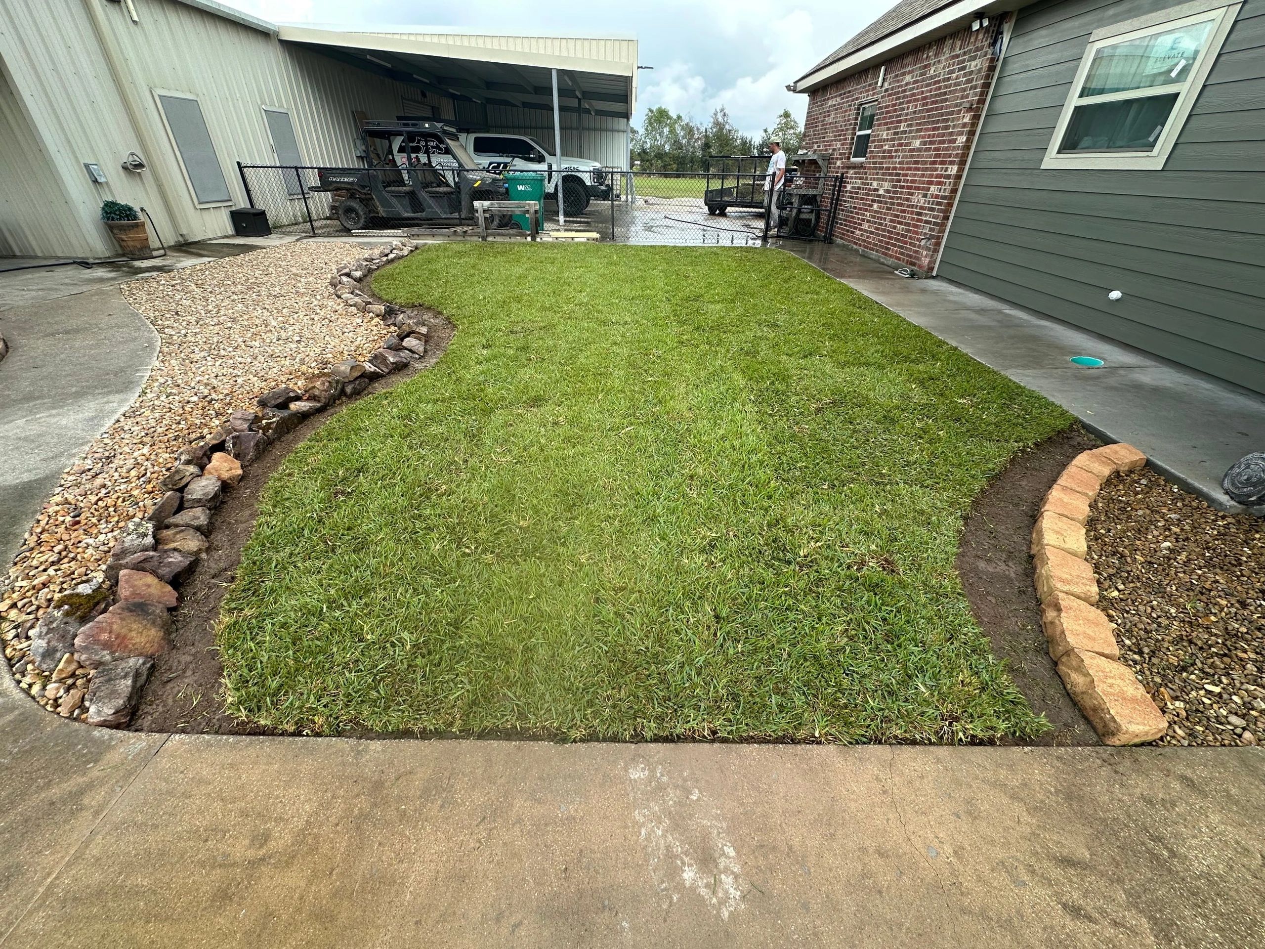 New sod and river-rock dry creek bed after a drainage fix in Holmwood by Lawson Landscaping