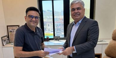 Two men exchanging documents in an office with smiles.