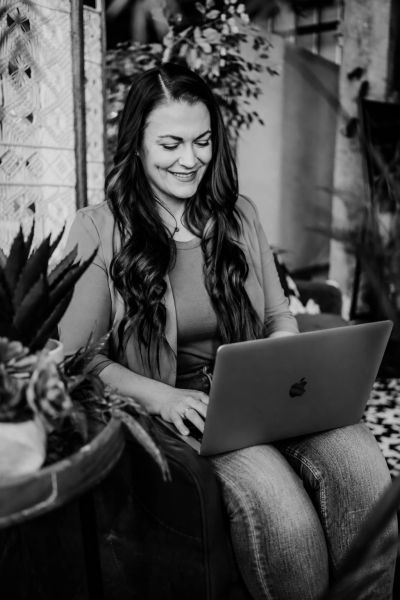 Woman smiling while using a laptop indoors.