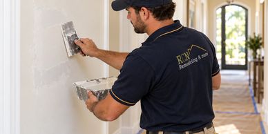 AI illustration: drywall repair by a tradesperson wearing an RCN work uniform.