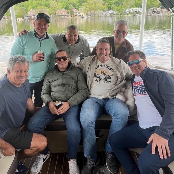 Group of seven men enjoying a boat ride on a calm lake.