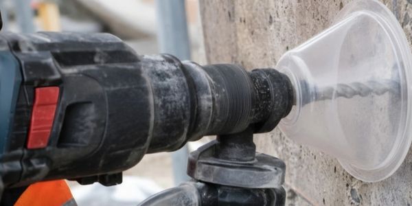 Power drill with hole saw on concrete wall.