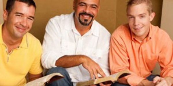 Three men smiling while holding Bibles