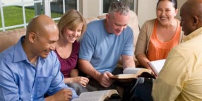Five adults smiling while looking at their Bibles