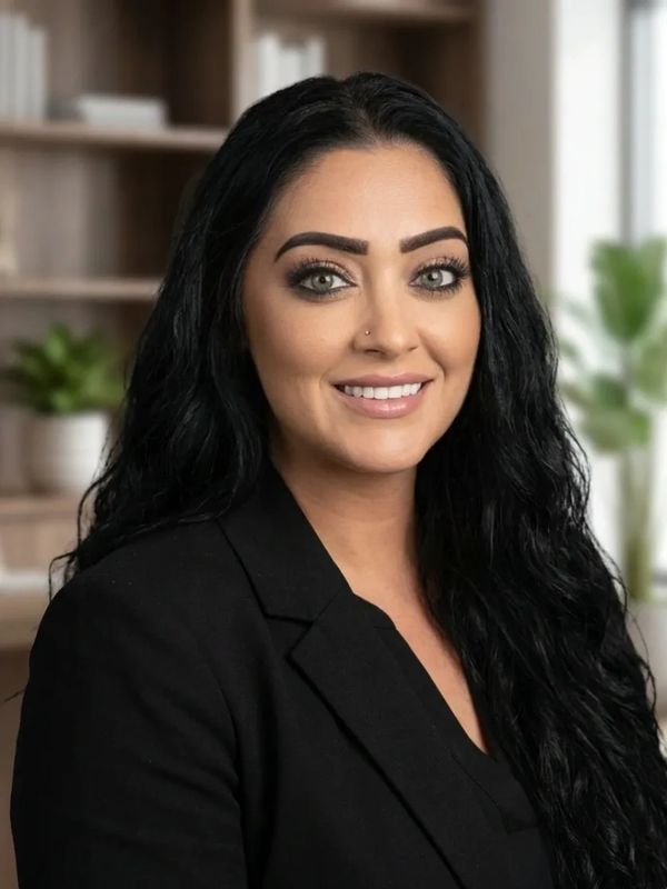 Professional woman with long black hair smiling in an office setting.