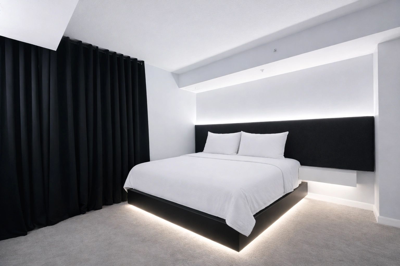 Modern bedroom with black and white decor and under-bed lighting.