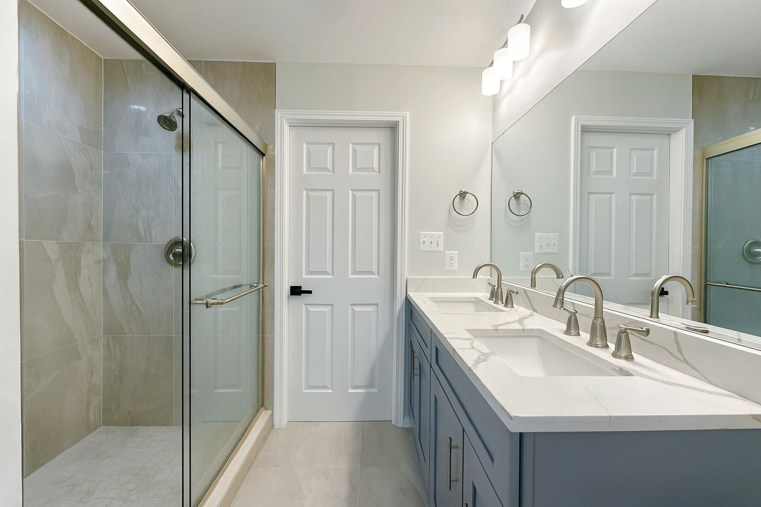Modern bathroom with dual sinks and a glass-enclosed shower.