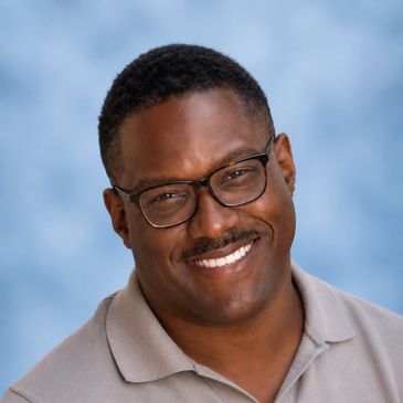 Smiling man wearing glasses and a polo shirt.