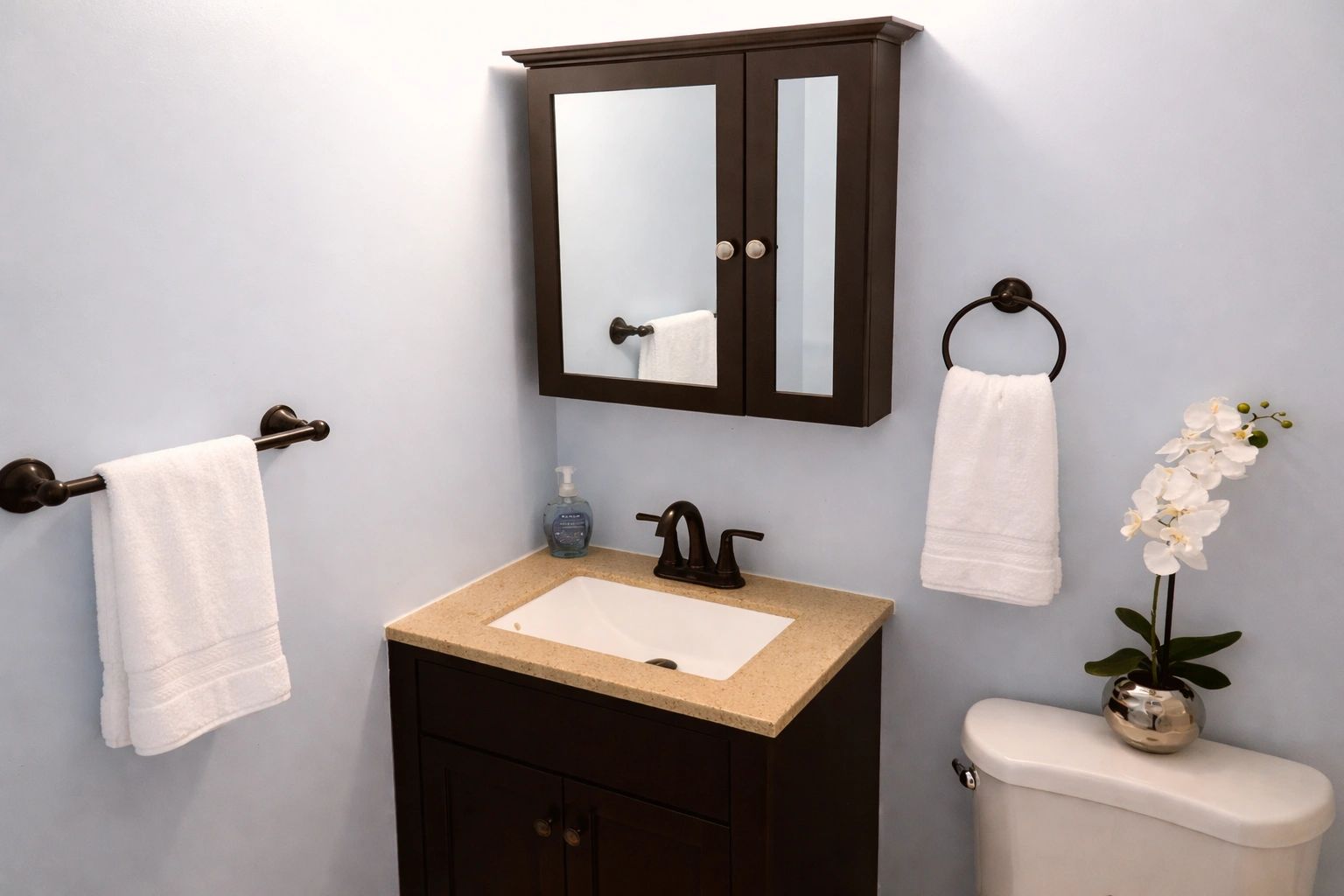Modern bathroom with dark wood vanity and white towels.
