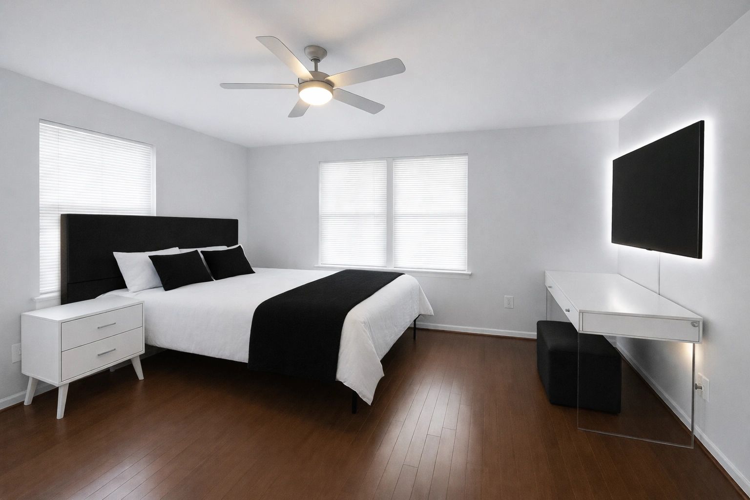Minimalist bedroom with black and white decor and wood flooring.