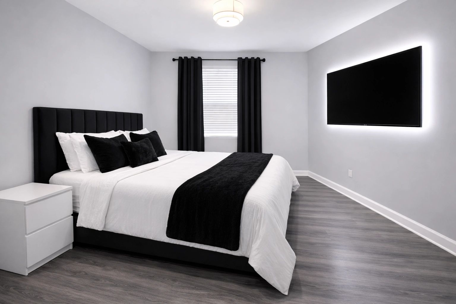 Modern bedroom with black and white decor and wall-mounted TV.