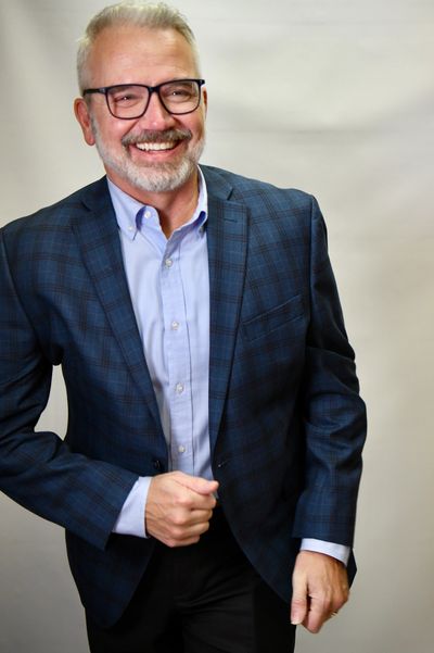 Smiling older man in glasses and plaid blazer.