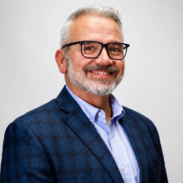 Smiling mature man in glasses and a blue plaid blazer.