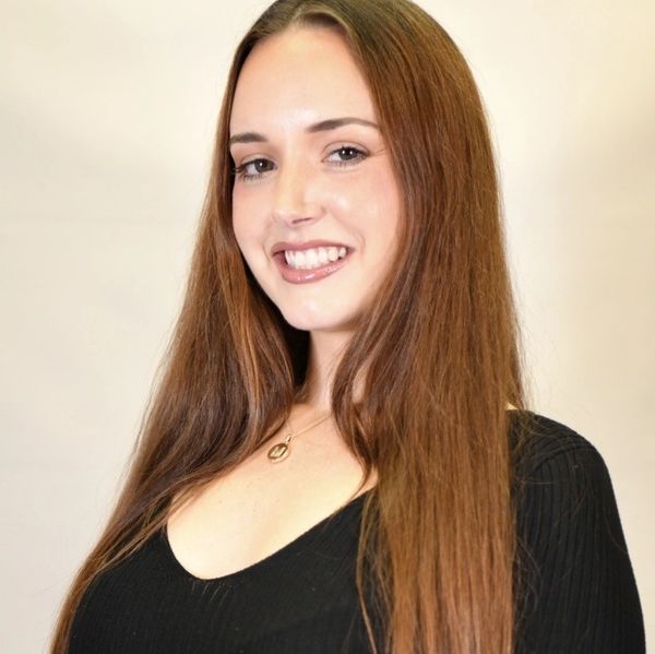 Smiling woman with long brown hair wearing a black top.