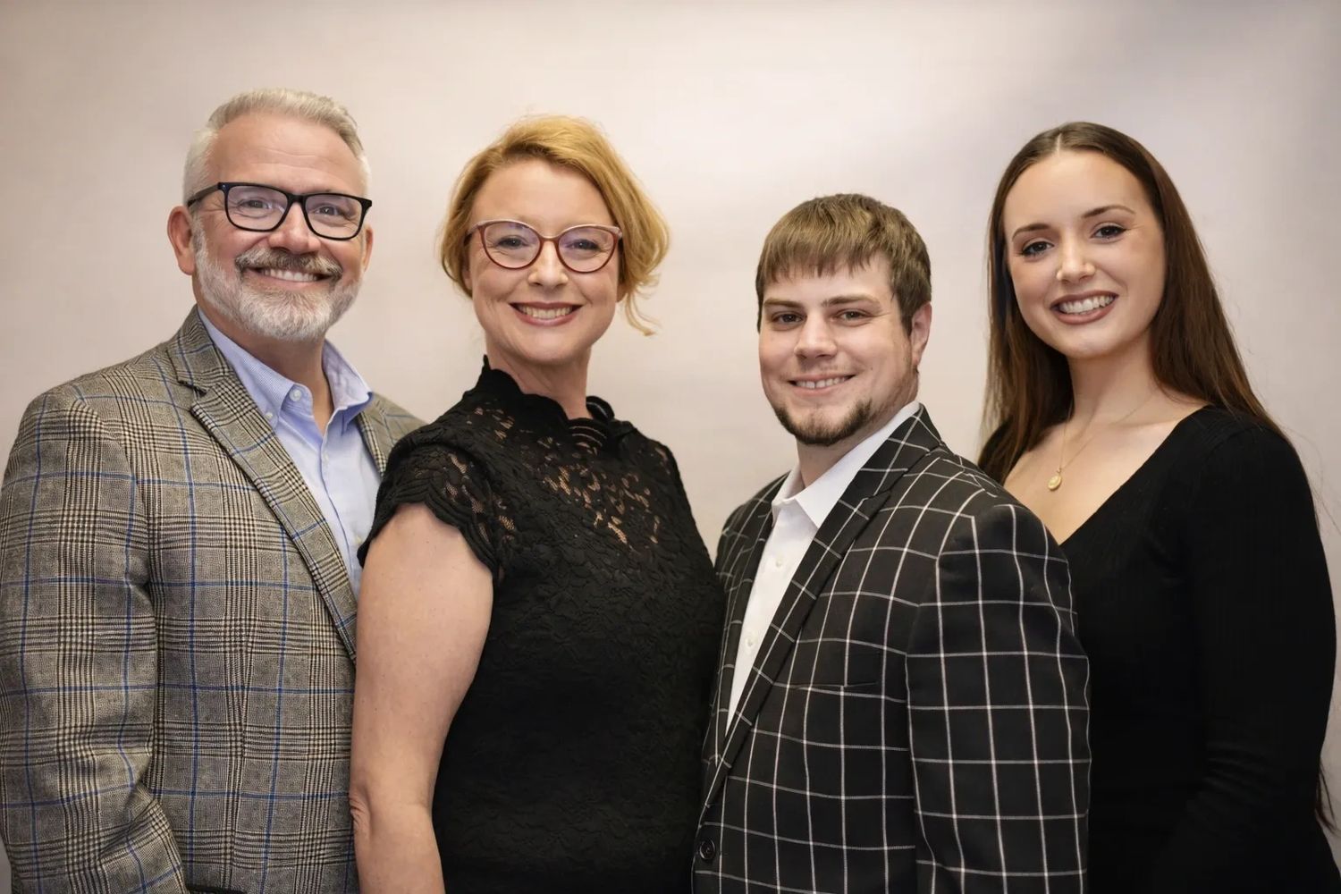 A smiling group of four adults in formal attire posing for a photo.