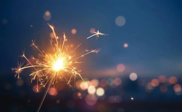 A glowing sparkler shining brightly against a dark background.