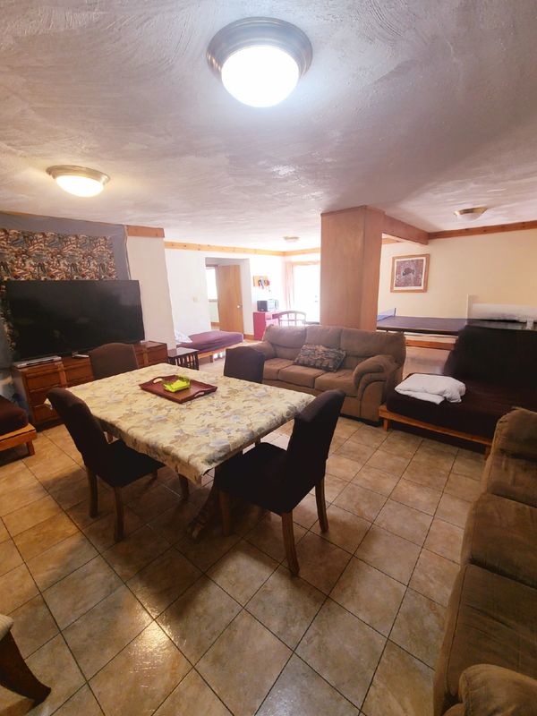 Cozy living room with dining table, couches, and TV in a warmly lit space.