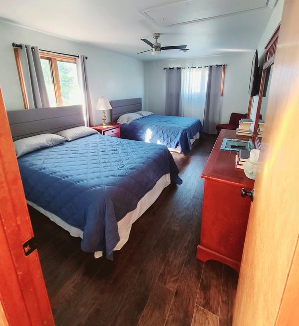 A cozy bedroom with two beds and blue bedding.