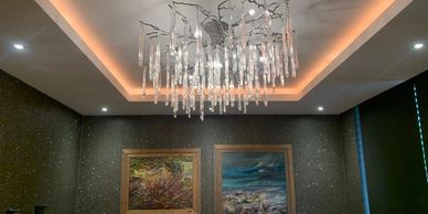 Modern chandelier with two paintings on the wall.
