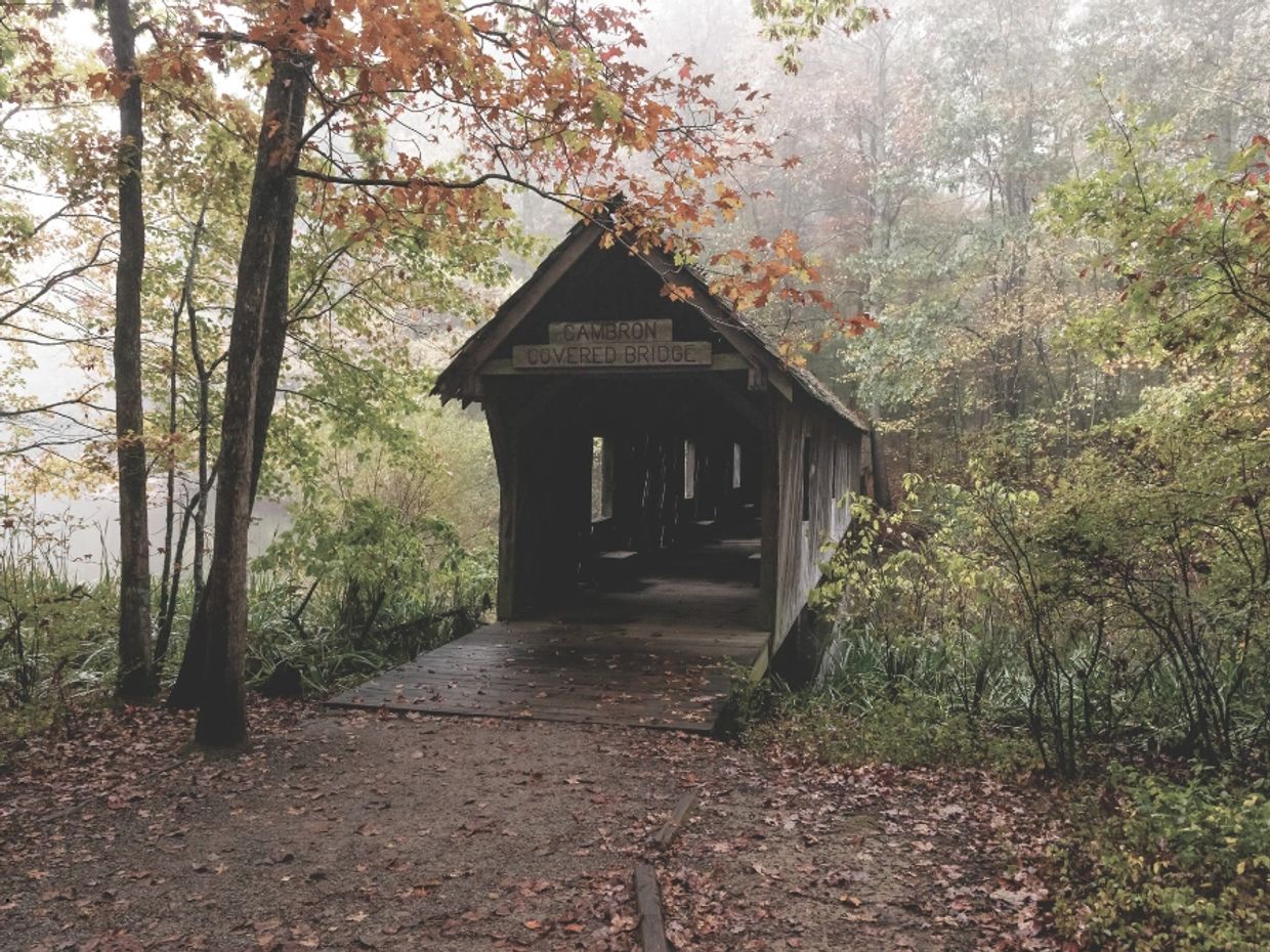 An old covered bridge in Alabama with title text “Scattering Ashes in Alabama” representing legal an