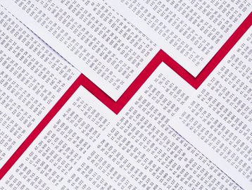 Red upward zigzag arrow over financial data sheets.