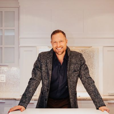 Man smiling, leaning on kitchen counter.