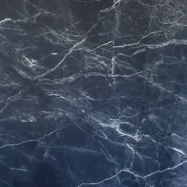 Black marble-patterned square mat with rounded corners on a wooden floor.