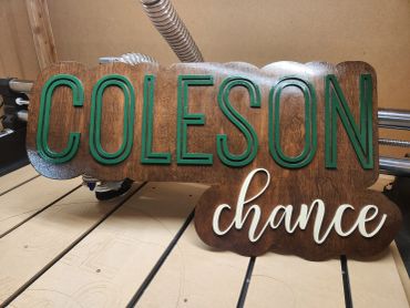 Wooden sign with green and white lettering saying 'COLESON chance'.