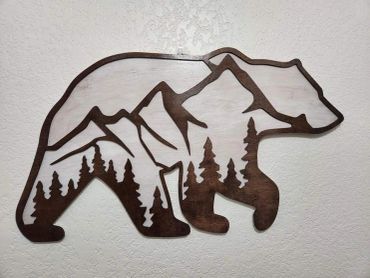 Wooden bear silhouette with mountain and tree carvings inside.