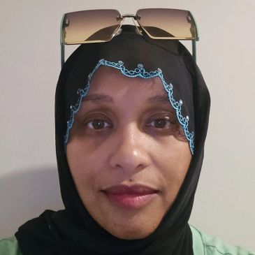 A woman wearing a black hijab with sunglasses resting on her head.