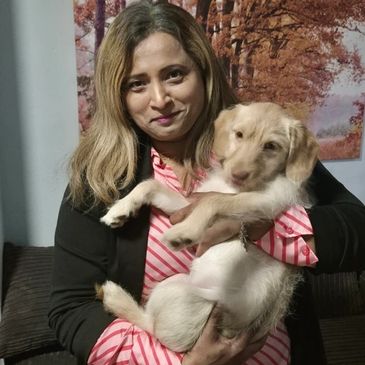 Woman holding a light brown puppy indoors, both looking content.