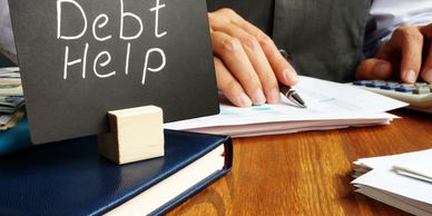 Hand writing financial documents with a sign saying "Debt Help".