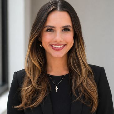 Professional young woman with long hair smiling, wearing a black blazer and cross necklace.